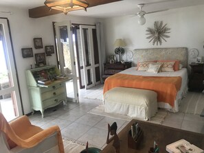 Quarto com cama, mesas de cabeceira, escrivaninha e uma cadeira.