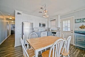 Kitchen area with central island, refrigerator, microwave, and dishwasher, plus a dining table and chairs.
