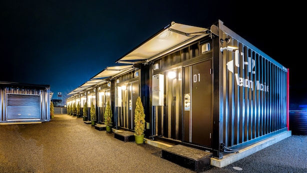 A row of modern, well-lit hotel rooms with a uniform design, featuring a large glass door and a small step leading to each room. - Hotel R9 The Yard Yaita (Yaita)