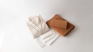 A neatly arranged set of towels and a folded robe on a white surface.