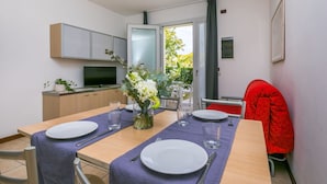 A modern kitchen with a dining area, a TV, and a view of the outdoors. - Nice apartment for 4 guests with A/C, WIFI, TV and terrace (Caorle)