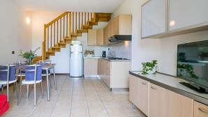 A modern kitchen with wooden cabinets, a built-in stove, and a refrigerator. - Nice apartment for 4 guests with A/C, WIFI, TV and terrace (Caorle)