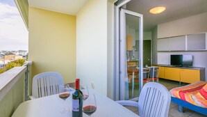 Un balcone con un tavolo apparecchiato per due persone, una bottiglia di vino e due bicchieri.