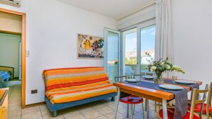 Una camera con un letto, un tavolo da pranzo con sedie e una finestra con tende.