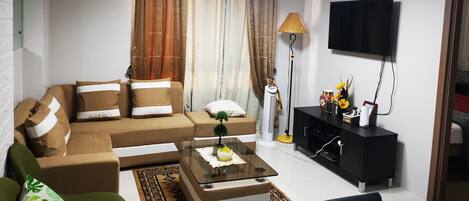 Una sala de estar moderna con un sofá, una mesa de centro y un televisor montado en la pared.