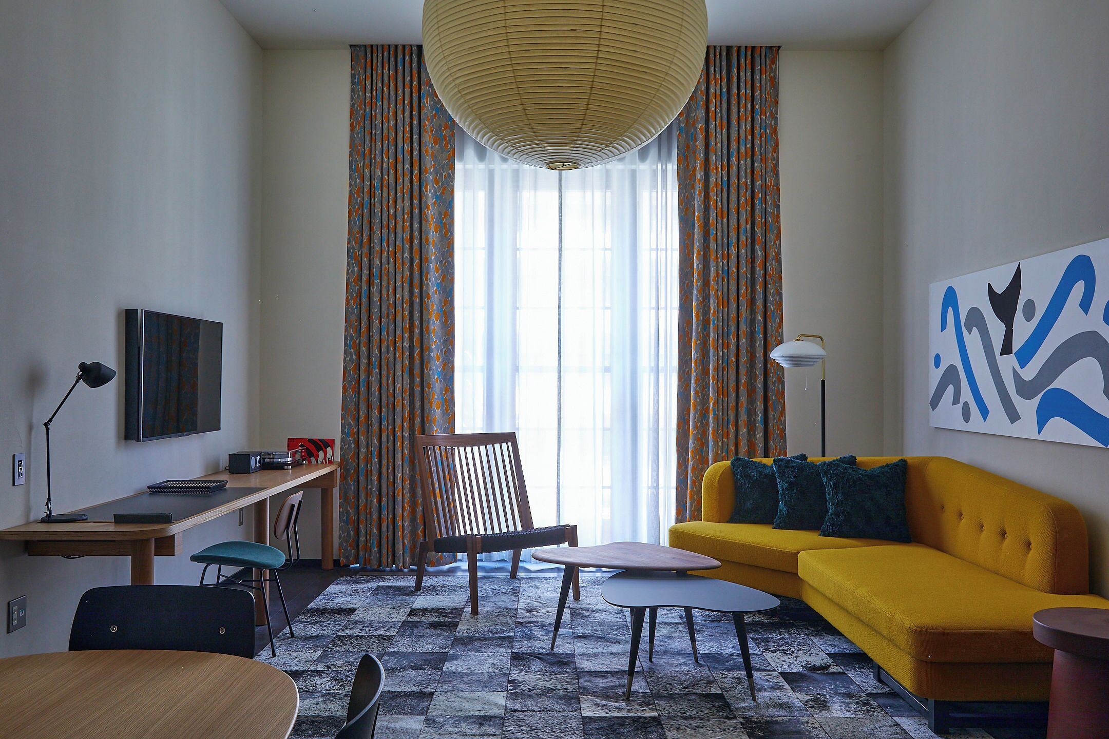 A modern living room with a sofa, a chair, a table, a lamp, and a TV.