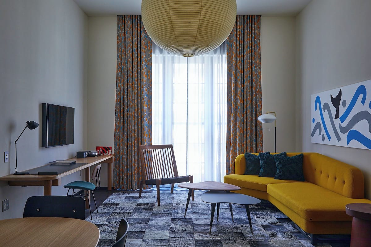 Un salon moderne comprenant un canapé, un fauteuil, une table, une lampe et un téléviseur.