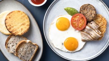 A breakfast plate with eggs, bacon, a tomato, and toast.
