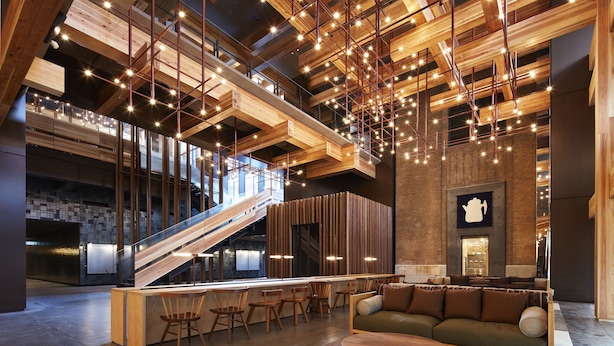 Un hall d’entrée spacieux avec un escalier en bois, un coin salon et une grande œuvre d’art accrochée au mur.