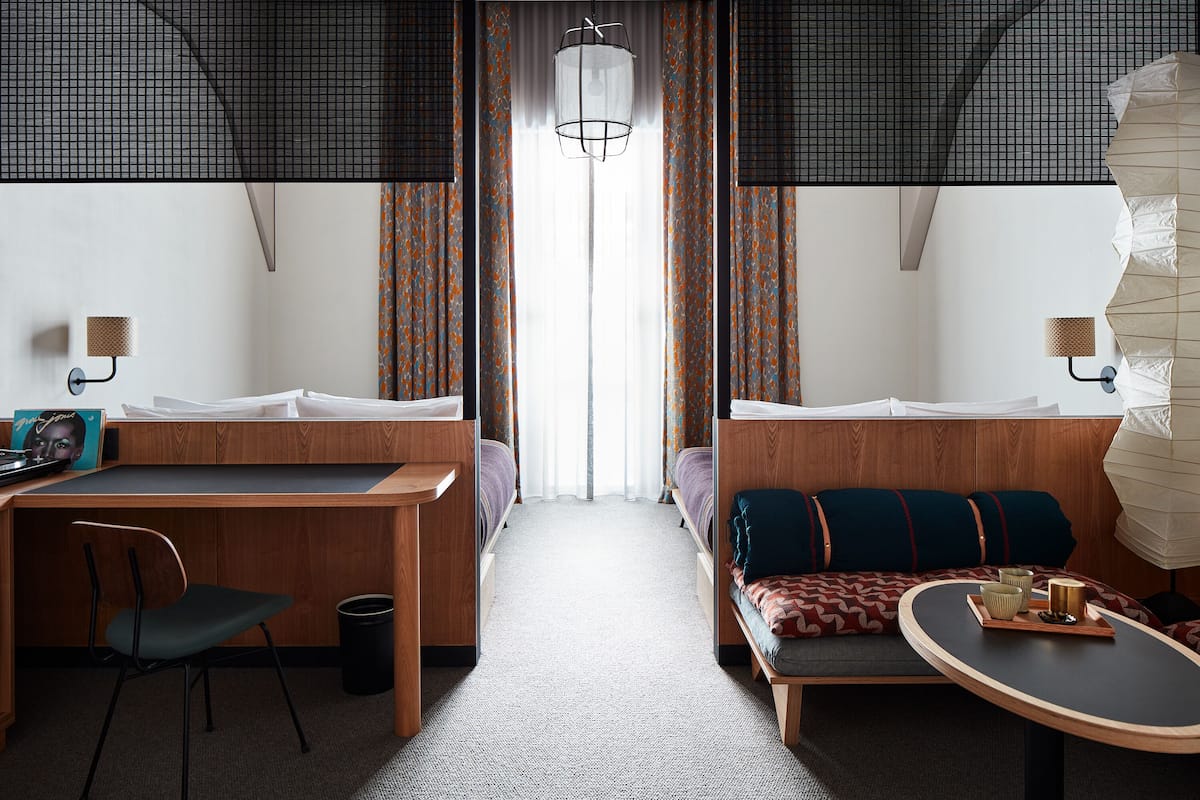 Une chambre d’hôtel compacte comprenant un bureau en bois, une chaise, un canapé et une petite table avec un plateau.