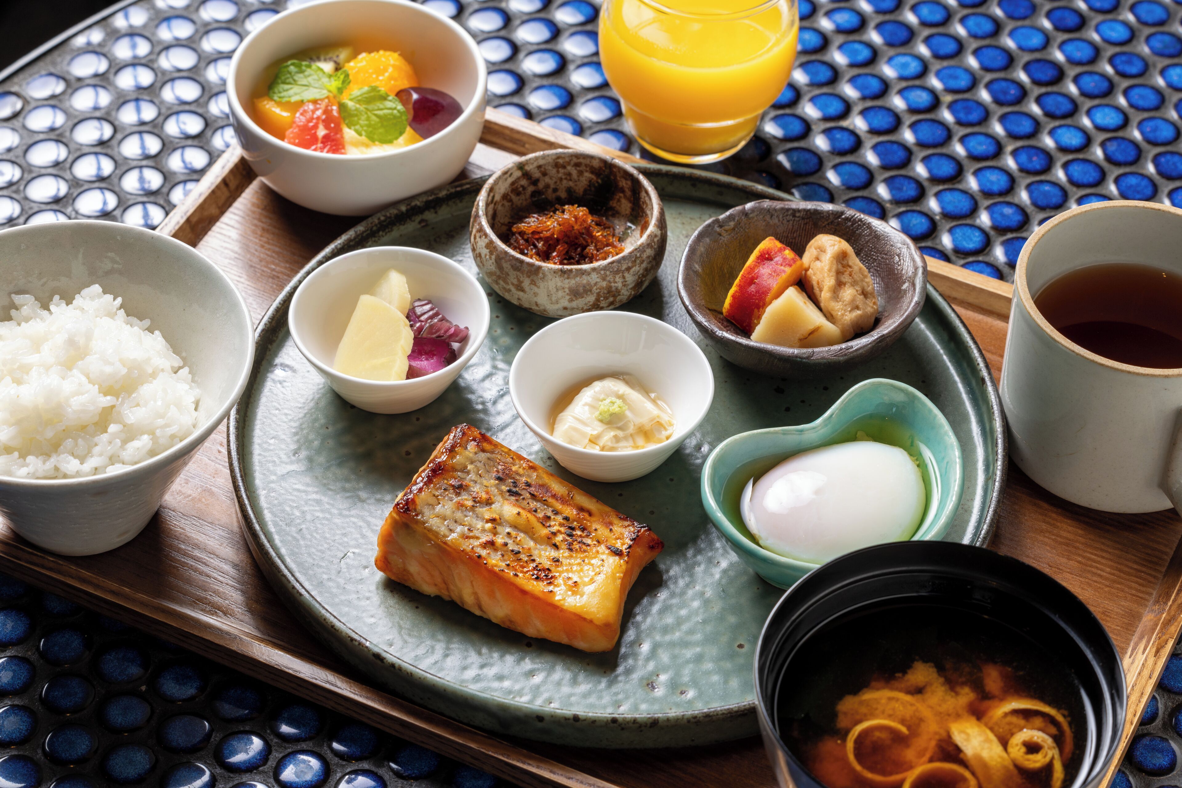 A tray with various food items including rice, a piece of grilled fish, and a bowl of soup.
