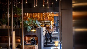 Un espace bar moderne doté d’une cabine de DJ, de sièges et d’un escalier menant au comptoir.