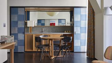 A modern kitchen with a wooden table and chairs, a built-in oven, and a large window with curtains.