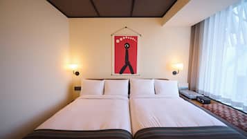 A hotel room with a double bed, two bedside lamps, a wall-mounted artwork, and a window with curtains.