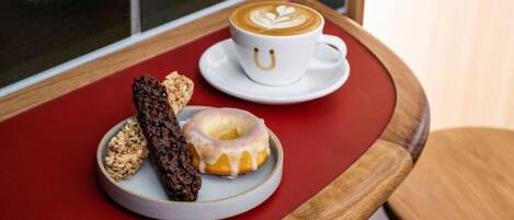 Una mesa con una taza de café, un donut y una barra de chocolate.