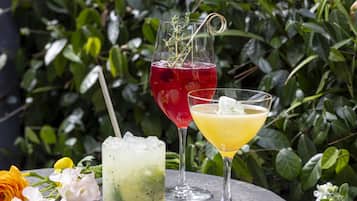Three drinks on a table with a green leafy background.
