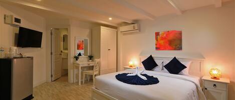 A hotel room with a bed, bedside tables, a TV, a desk, and a wardrobe.