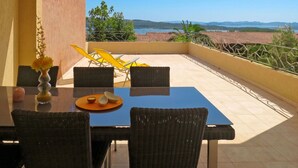 Un balcón con mesa, sillas y vista al mar.