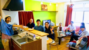 A modern kitchen with a wooden countertop, stainless steel sink, and a dining area with a sofa and table. - Guesthouse LuLuLu Atago (Kochi)