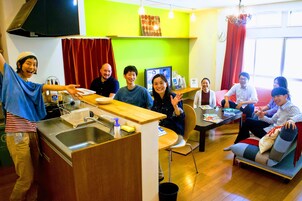 Una cocina moderna con encimera de madera, pileta de acero inoxidable y un comedor con sofá y mesa.