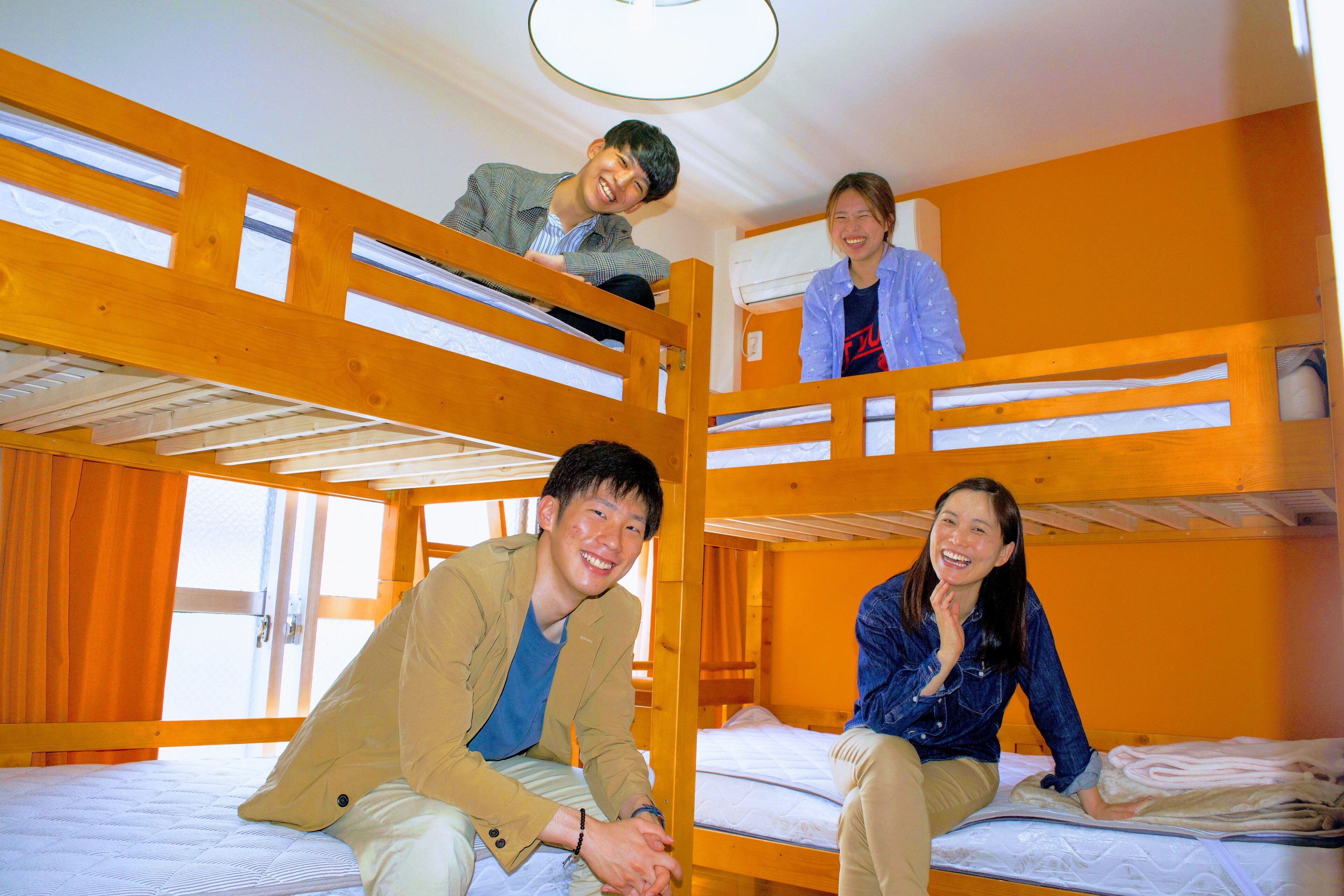Habitación con literas donde dos personas están sentadas en la cama inferior y una persona de pie en la superior.