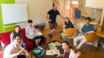 A group of people in a room with a whiteboard, a table with magazines, and a counter with a water bottle.