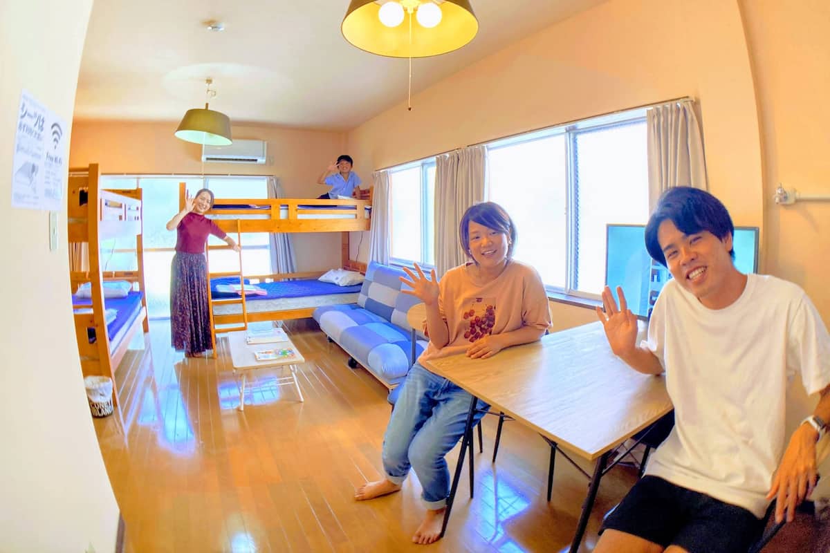 A room with bunk beds, a sofa, a table, and a hanging light fixture.