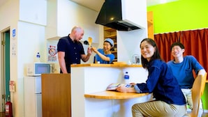 A room with a wooden counter, a microwave, a refrigerator, and a fire extinguisher. - Guesthouse LuLuLu Atago (Kochi)
