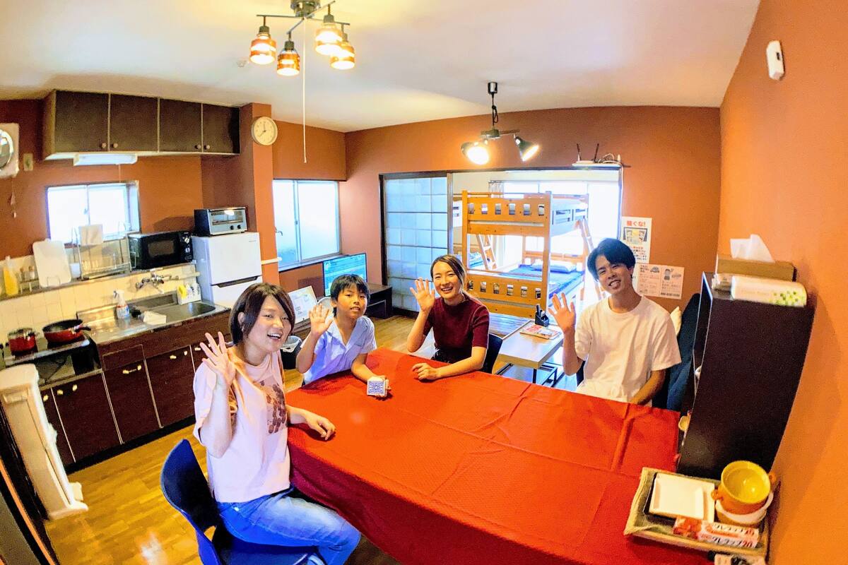 A group of people seated around a table in a room with a kitchen area visible in the background.