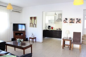 A living room with a television, a coffee table, a sofa, and a dining area with a table and chairs.