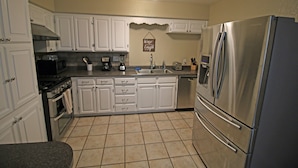 A kitchen with white cabinets, a stainless steel refrigerator, a microwave, and a stove.