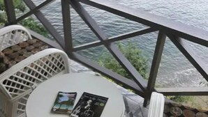 A small outdoor seating area with a round table and two white wicker chairs, overlooking a body of water. - Serene, breathtaking beauty, friendly environment. (Parlatuvier)