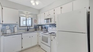Une cuisine moderne avec des meubles blancs, un four à micro-ondes encastré, une cuisinière et un réfrigérateur.