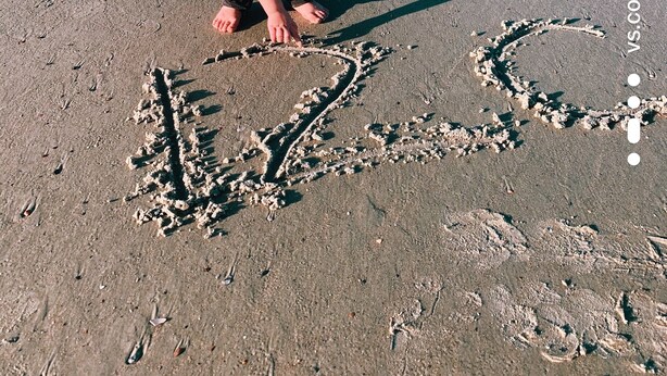 Un enfant qui dessine dans le sable sur la plage.