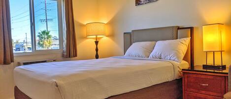 A neatly made bed with white linens, a headboard, and two bedside lamps.