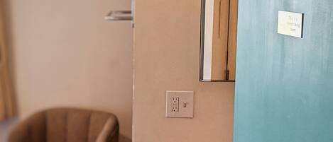 A room with a blue door marked with the number 20, a sink, a mirror, and a chair.