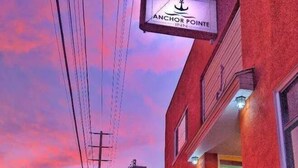 Ein Gebäude mit einem Schild, auf dem „Anchor Pointe Inn“ steht, vor einem Sonnenuntergangshimmel.