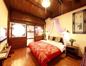 Una habitación tradicional con techo de madera, una cama con colcha de rayas rojas y blancas, un dosel y un aire acondicionado instalado en la pared.