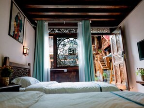 A bedroom with a bed, a headboard, a wall-mounted light, and a window with curtains. - Lijiang shuimuxiquan Inn (Lijiang)