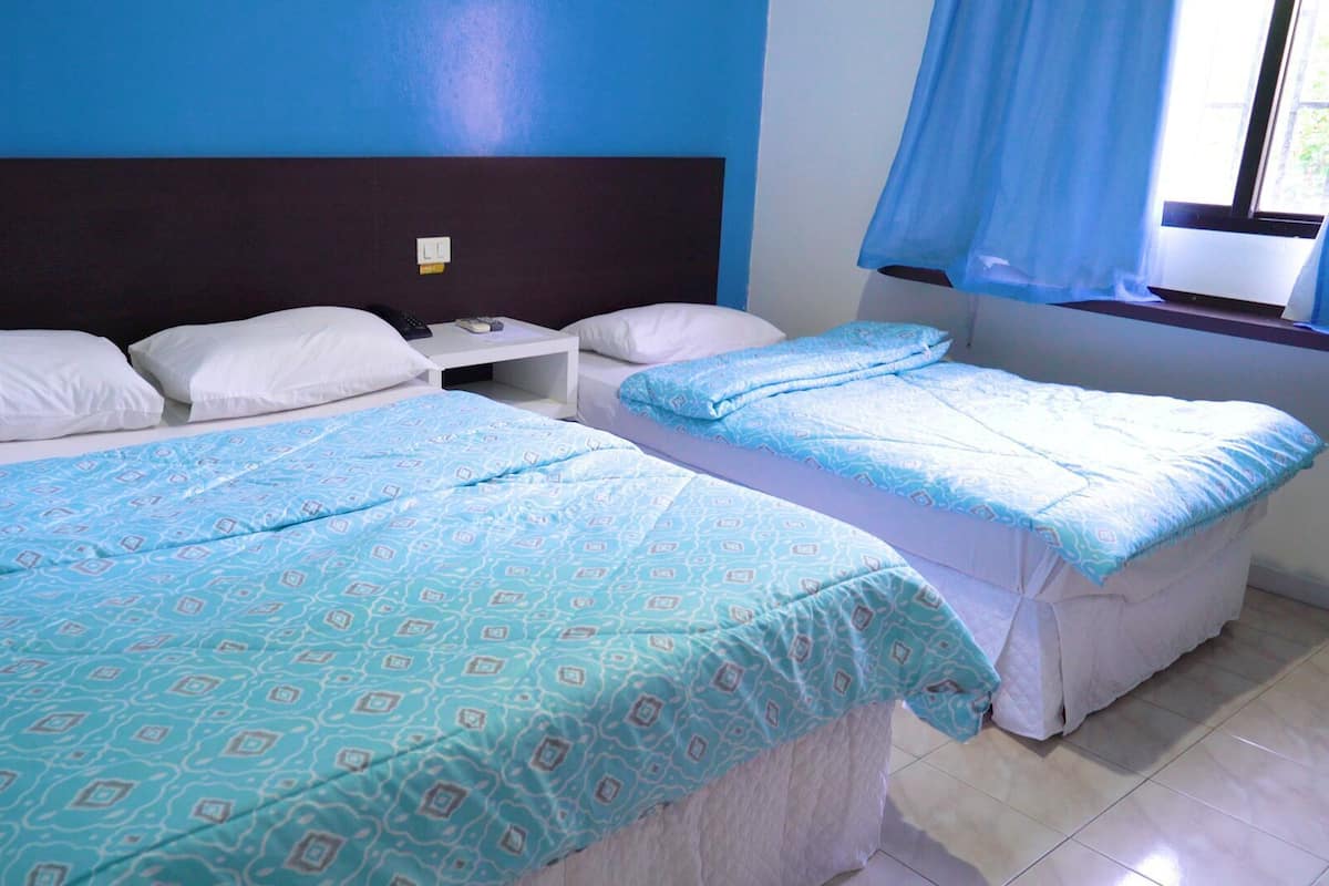 A hotel room with two beds, a nightstand, and a window with curtains.