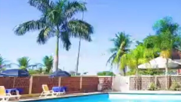 A swimming pool with lounge chairs and umbrellas, surrounded by palm trees. - Itacaiunas Hotel (Maraba)