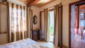 A bedroom with a bed, wooden ceiling beams, a dresser, and a mirror. There is a door leading to a balcony. - Nice apartment in villa for 4 guests with WIFI, TV, terrace and pets allowed (Barabarca)