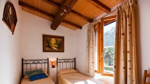 A bedroom with two single beds, a wooden ceiling, a painting on the wall, and a window with curtains. - Nice apartment in villa for 5 people with WIFI, TV, terrace and pets allowed (Barabarca)
