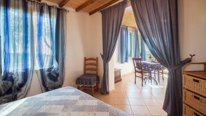 A room with a bed, a chair, a table, and curtains. - Beautiful apartment in villa for 2 people with WIFI, TV, terrace and pets allowed (Capoliveri)
