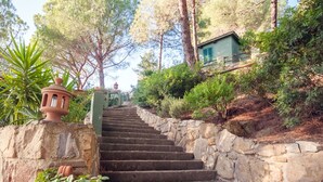 A stone staircase leading up to a building with a green roof, surrounded by trees and plants. - Beautiful apartment in villa for 2 people with WIFI, TV, terrace and pets allowed (Capoliveri)