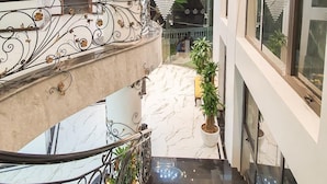A modern hotel interior with a marble staircase, decorative metal railings, and a glass-enclosed balcony. - La Stella Hotel (Bai Chay)
