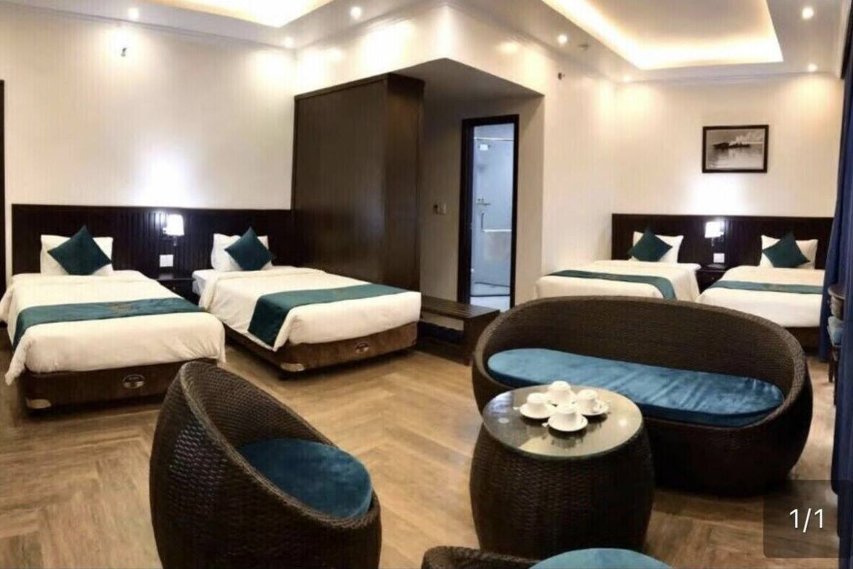A hotel room with two beds, a large window, a door, and a seating area with a table.