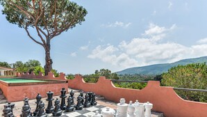 A large outdoor chessboard with pieces, surrounded by a stone wall and a tree, overlooking a scenic landscape. - Beautiful apartment for 5 people with pool, A/C, WIFI and terrace (Capoliveri)