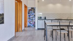 Une cuisine moderne avec un coin repas, comprenant une porte en bois, un collage mural et un pare-feu en carreaux.