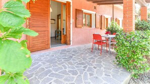 Un patio de piedra con una mesa y sillas, una puerta de madera y un muro de ladrillo.